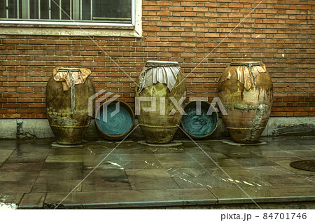 Ancient earthenware jugs for wine, oil, with copper cauldrons are exhibited at the brick wall of the Museum of Decorative and Applied Arts in Tehran 84701746