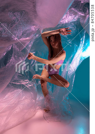 Dynamic portrait of young flexible contemp dancer dancing with fabric isolated on gradient blue white background in neon light 84705538