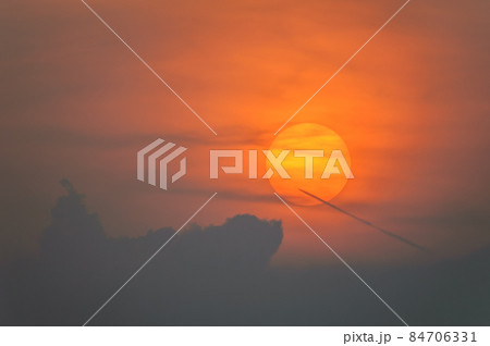 Sun disk through the clouds at sunset above the horizon. France. 84706331