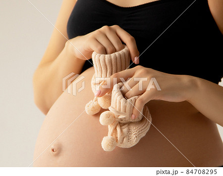 Small shoes for the unborn baby in the belly of 84708295