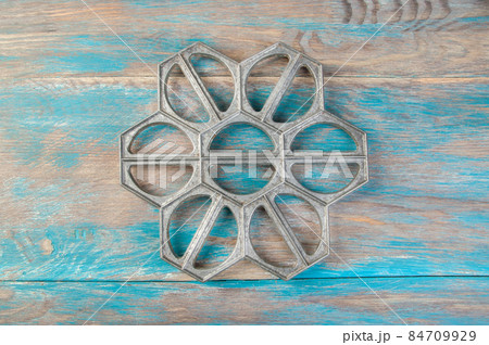 Old aluminum dumplings mold on blue wooden background. 84709929