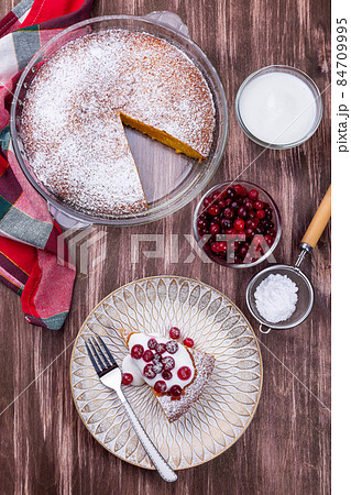 Piece of Swedish saffron Kladdkaka pie with white chocolate, whipping cream and cranberry, vertical Piece of Swedish saffron Kladdkaka pie with white chocolate, whipping cream and cranberry, vertical 84709995