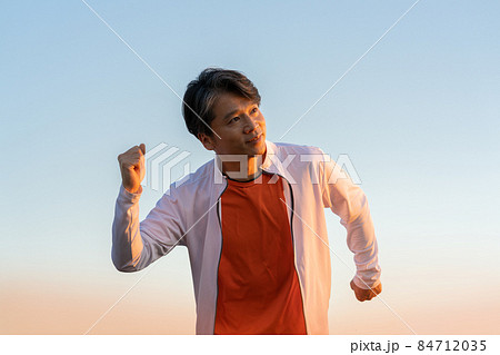 夕陽を浴びて走る中年男性の上半身 84712035