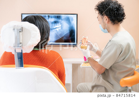 歯科医院で患者さんに模型を使い説明するドクターの様子	 84715814