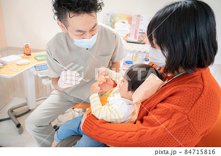 頑張って幼児の口を開けようとする小児歯科医1 84715816