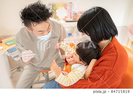頑張って幼児の口を開けようとする小児歯科医4 84715819