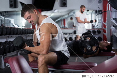 Man exercising with dumbbells in gym 84716597
