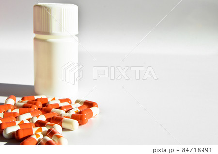 Orange and white capsule pills and white medicine box, isolated on white background Orange and white capsule pills and white medicine box, isolated on white background 84718991