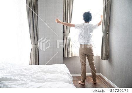 部屋の中で逆光の朝日を浴びてストレッチをする美しい日本人男性 部屋の中で逆光の朝日を浴びてストレッチをする美しい日本人男性 84720175