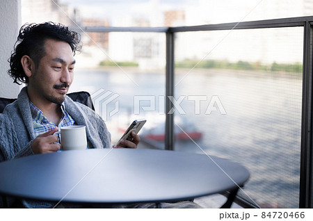 ベランダでくつろぎながらスマホを見る日本人男性7 クローズアップ ベランダでくつろぎながらスマホを見る日本人男性7 クローズアップ 84720466