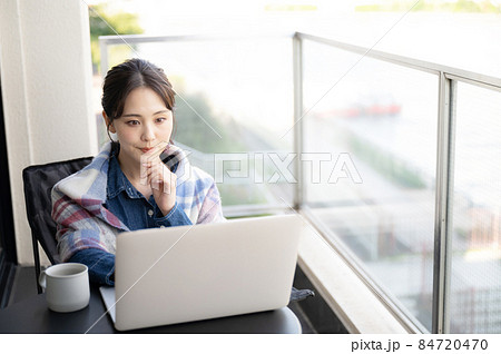 ベランダでくつろぎながらパソコンをしてちょっと考える表情の日本人女性1 アップ コピースペースあり	 84720470