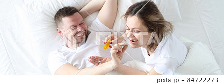 Man gives woman a birth control pill on bed Man gives woman a birth control pill on bed 84722273