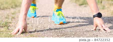Active man in low starting position prepares for sprint in park 84722352