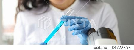 Scientist hands in gloves holds test tube with blue liquid in laboratory 84722353