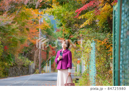 秋の風景の中にいるスマートフォンを持った女性 秋の風景の中にいるスマートフォンを持った女性 84725980