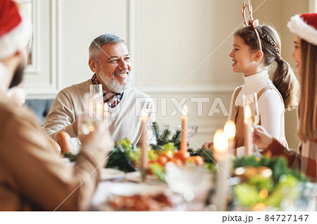 Happy multi generation family in Santa hats at dinner table, saying xmas toasts and clinking glasses 84727147