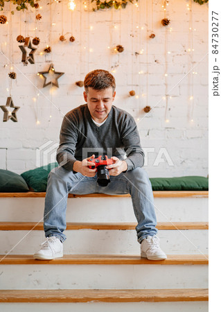 man with red camera against white wall decorated for new year. photographer 84730277