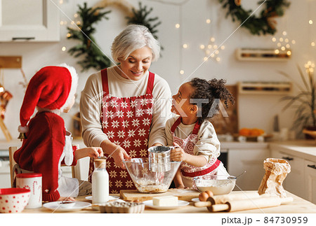 Happy multiracial kids help grandmother to cook Christmas cookies in kitchen during winter holidays Happy multiracial kids help grandmother to cook Christmas cookies in kitchen during winter holidays 84730959