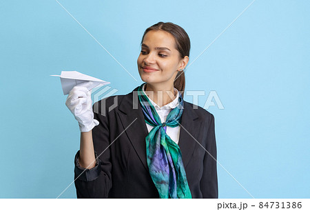 Half-length portrait of beautiful young girl, flight attendant in black uniform posing isolated on blue studio background. Half-length portrait of beautiful young girl, flight attendant in black uniform posing isolated on blue studio background. 84731386