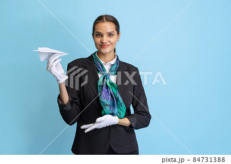 Half-length portrait of beautiful young girl, flight attendant in black uniform posing isolated on blue studio background. Half-length portrait of beautiful young girl, flight attendant in black uniform posing isolated on blue studio background. 84731388
