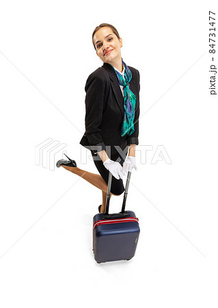 High angle view of beautiful young girl, flight attendant in uniform with suitcase isolated on white studio background. High angle view of beautiful young girl, flight attendant in uniform with suitcase isolated on white studio background. 84731477