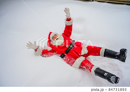 Happy santa claus lying in the snow and fooling around 84731893