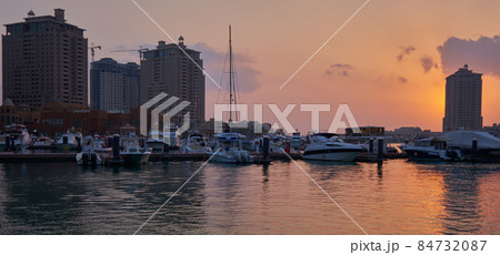 Porto Arabia marina in the Peral Doha, Qatar sunset shot showing Docking boats and yachts, kayak training in the Arabic gulf and residential buildings in back ground Porto Arabia marina in the Peral Doha, Qatar sunset shot showing Docking boats and yachts, kayak training in the Arabic gulf and residential buildings in back ground 84732087