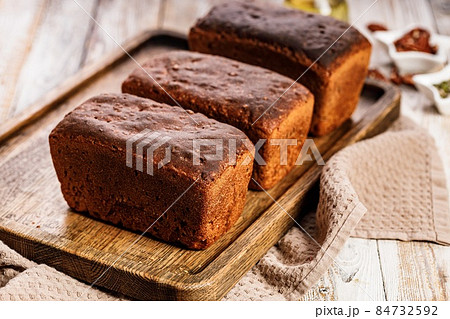 Organic rye bread loafs. Fresh bread made from whole grain rye flour. Homemade delicious pastries on a wooden tray on a rustic background. Close-up. Copy space Organic rye bread loafs. Fresh bread made from whole grain rye flour. Homemade delicious pastries on a wooden tray on a rustic background. Close-up. Copy space 84732592
