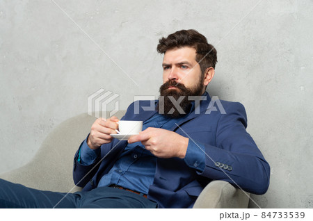 Bearded man relax drinking tea or coffee in rest armchair during work break, relaxing 84733539