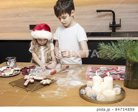 Children - a boy and a girl are preparing gingerbread in the kitchen 84734899
