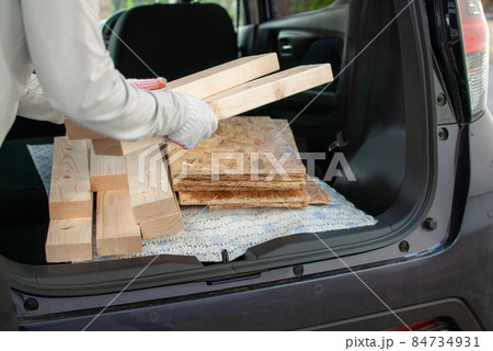 軽自動車のトランクから木材を運ぶ女性の手元 84734931