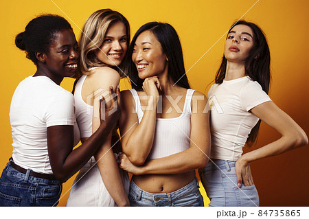 diverse multi nation girls group, teenage friends company cheerful having fun, happy smiling, cute posing on yellow background, lifestyle people concept, african-american, asian and caucasian 84735865