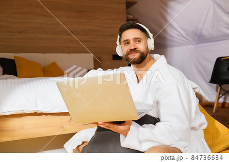Young bearded man with headphones and laptop Young bearded man with headphones and laptop 84736634