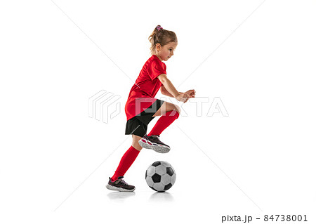 Full-lenght portrait of little sportive girl in red uniform playing team game, training football isolated over white background Full-lenght portrait of little sportive girl in red uniform playing team game, training football isolated over white background 84738001