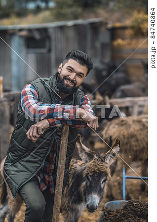 Dark-haired man resting after cleaning the cattle-pen 84740864