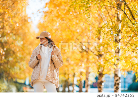 Fall concept - beautiful woman drinking coffee in autumn park under fall foliage Fall concept - beautiful woman drinking coffee in autumn park under fall foliage 84742355