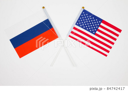 Russia flag and USA flag crossed with each other on the white background. Russia vs USA. Meeting between the presidents of the Russia and United States. Isolated. Top view Russia flag and USA flag crossed with each other on the white background. Russia vs USA. Meeting between the presidents of the Russia and United States. Isolated. Top view 84742417