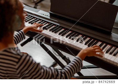 Multiracial young woman playing synthesizer at home Multiracial young woman playing synthesizer at home 84742669