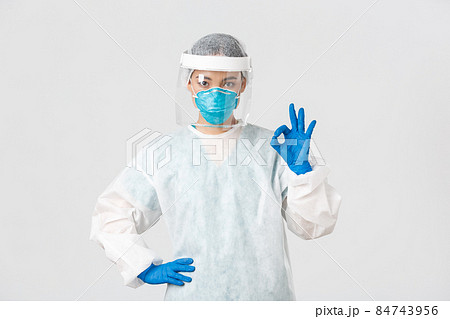 Covid-19, coronavirus disease, healthcare workers concept. Serious-looking professional female asian doctor in personal protective equipment, showing okay gesture, ensure safety of patient 84743956