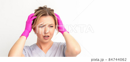 The emotionally shocked young female medical worker holding hands on her head fell into panic on white background, infection, epidemic, virus, and disease concept. The emotionally shocked young female medical worker holding hands on her head fell into panic on white background, infection, epidemic, virus, and disease concept. 84744062