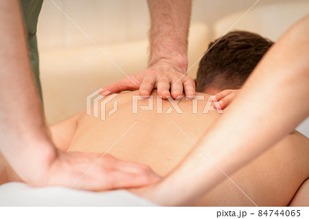 Young man receiving back massage in four hands in spa beauty salon. 84744065