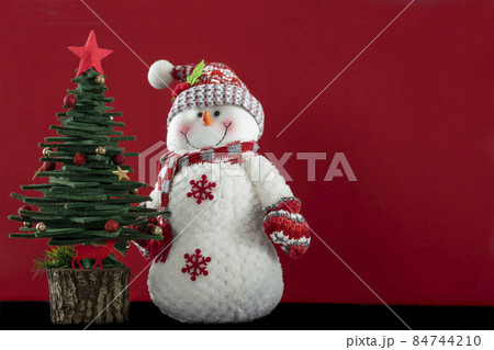 Christmas greeting background with pine tree and Snowman ornaments isolated on red surface with copy space 84744210