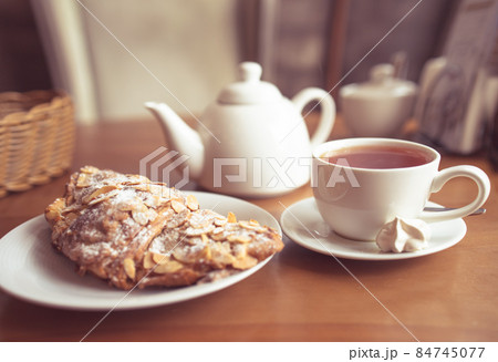 Tea cup, teapot and croissant on table in cafe Tea cup, teapot and croissant on table in cafe 84745077