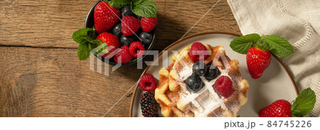 Belgian waffles with summer fruits on plate on dark wooden background. Belgian waffles with summer fruits on plate on dark wooden background. 84745226