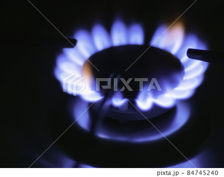 Blue flames of a gas in gas cooker. Fire on stove in dark. 84745240