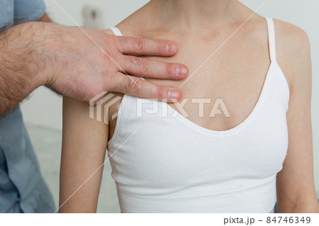 Female patient receiving osteopathic neck and shoulder treatment. Therapist manipulating back of head and chest. A girl receiving CST treatment. Osteopathic manipulation and therapy. 84746349