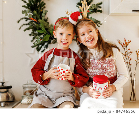 Smiling happy children boy and girl in aprons cooking on Christmas day in cozy decorated kitchen 84746556