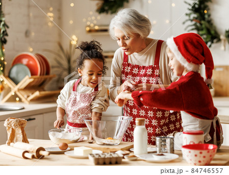 Happy multiracial kids help grandmother to cook Christmas cookies in kitchen during winter holidays Happy multiracial kids help grandmother to cook Christmas cookies in kitchen during winter holidays 84746557