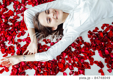 a beautiful woman lies in the petals of red rose flowers a beautiful woman lies in the petals of red rose flowers 84748049