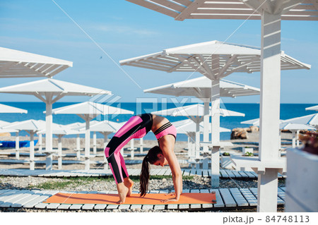 beautiful woman engaged in fitness gymnastics yoga asana on the beach by the sea beautiful woman engaged in fitness gymnastics yoga asana on the beach by the sea 84748113